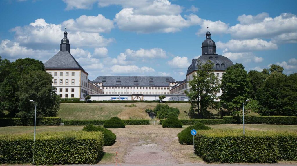Schloss Friedenstein mit zwei Türmen und einer grünen Landschaft im Vordergrund.