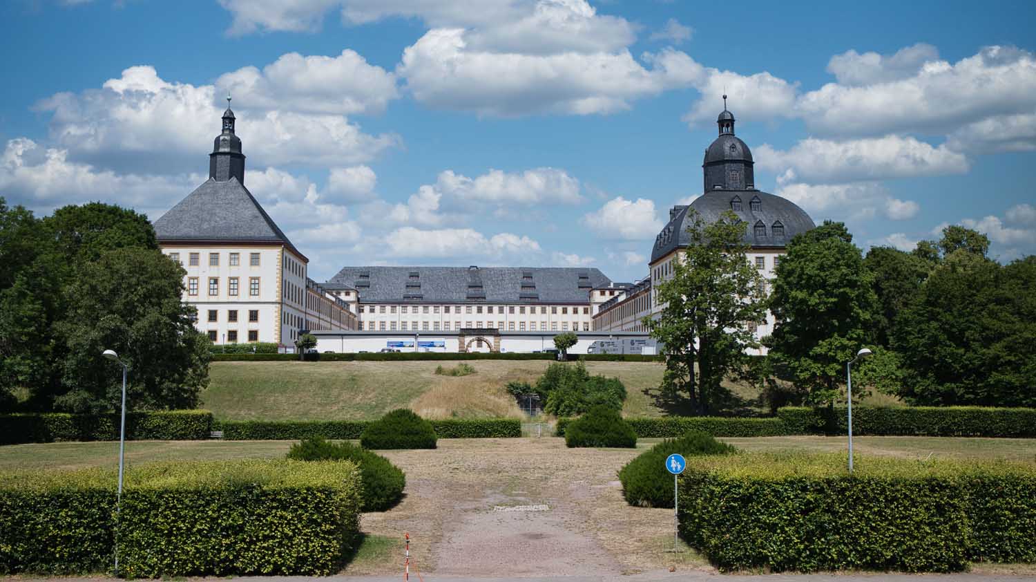 Schloss Friedenstein mit zwei Türmen und einer grünen Landschaft im Vordergrund.